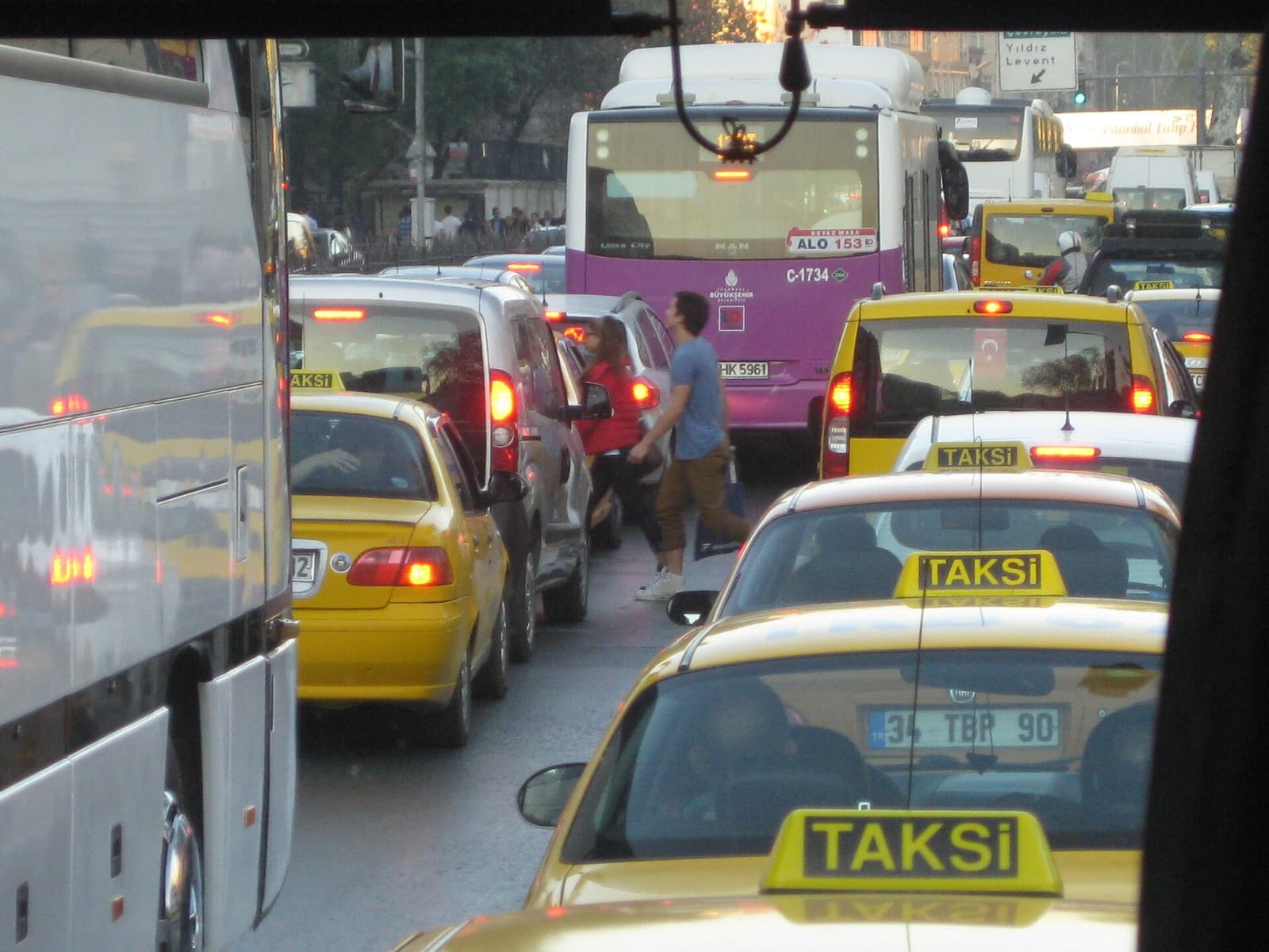 İstanbul'da yoğun trafik: taksiler, bir belediye otobüsü ve araçların arasından karşıya geçen yayalar